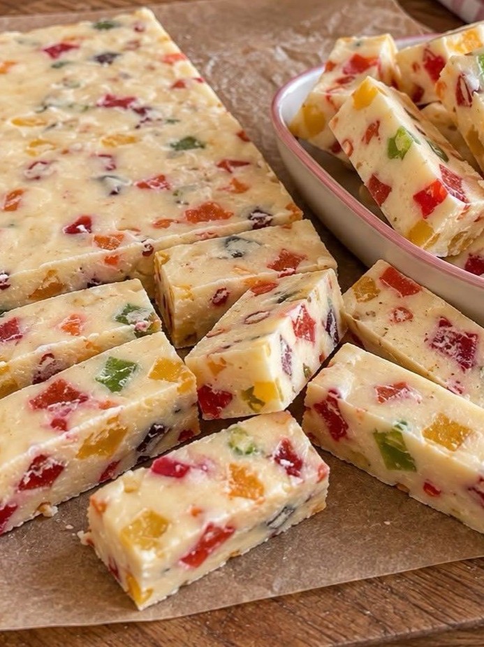 Close-up of several homemade soft torrone bars, showcasing the creamy white nougat embedded with blanched almonds.